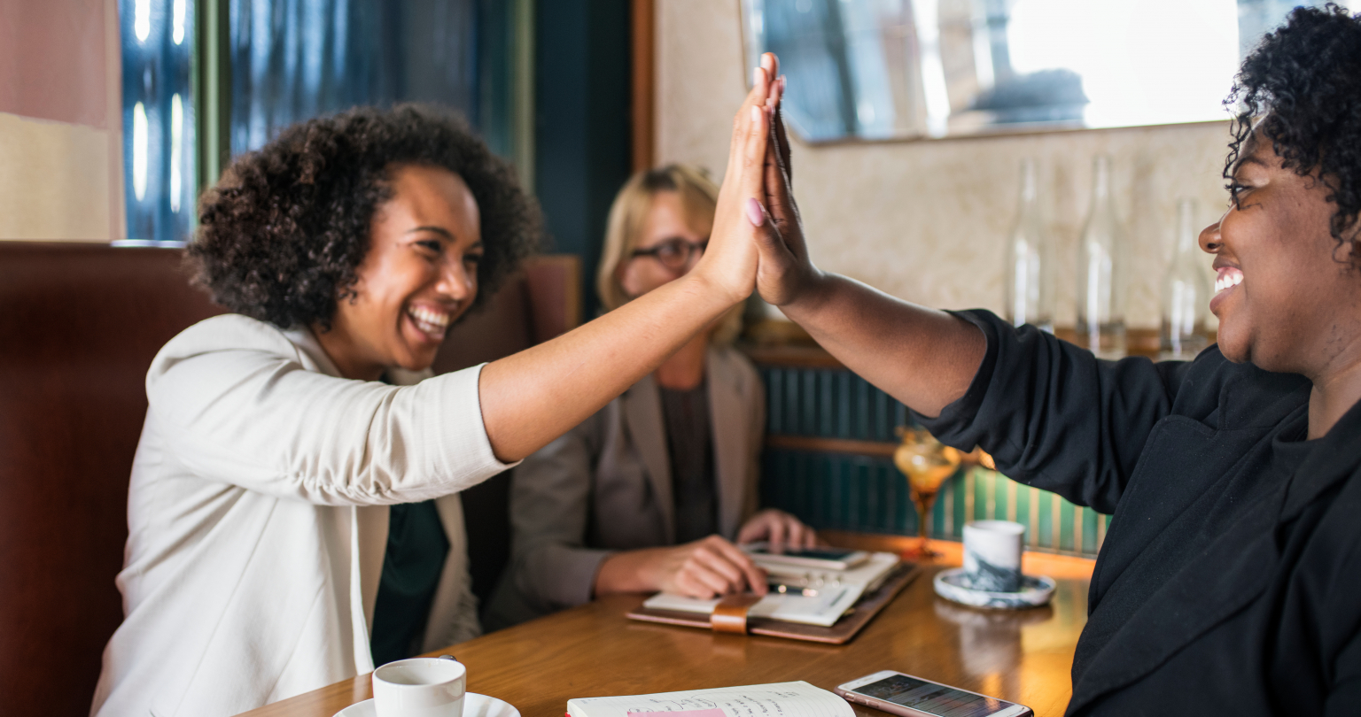 Successful businesswomen giving a high five to a colleague.